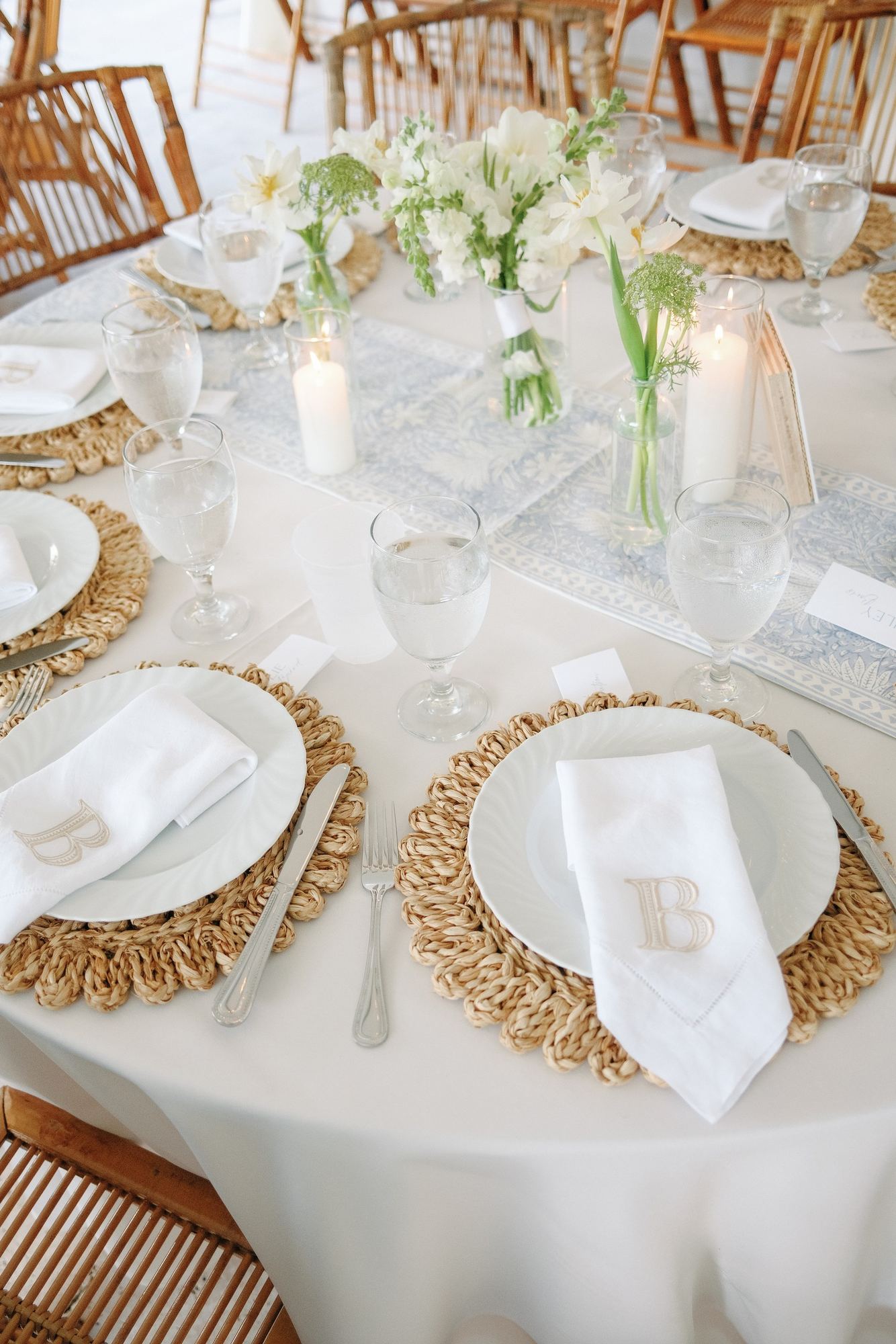 Round table with a pale blue block-printed runner and monogrammed napkins