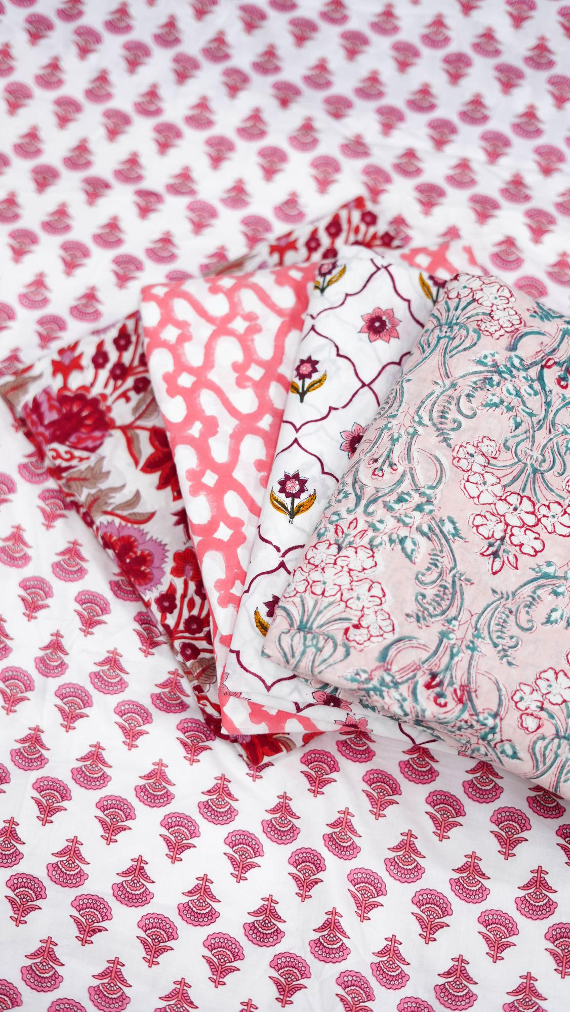 Folded stack of pink and coral block-printed cottons