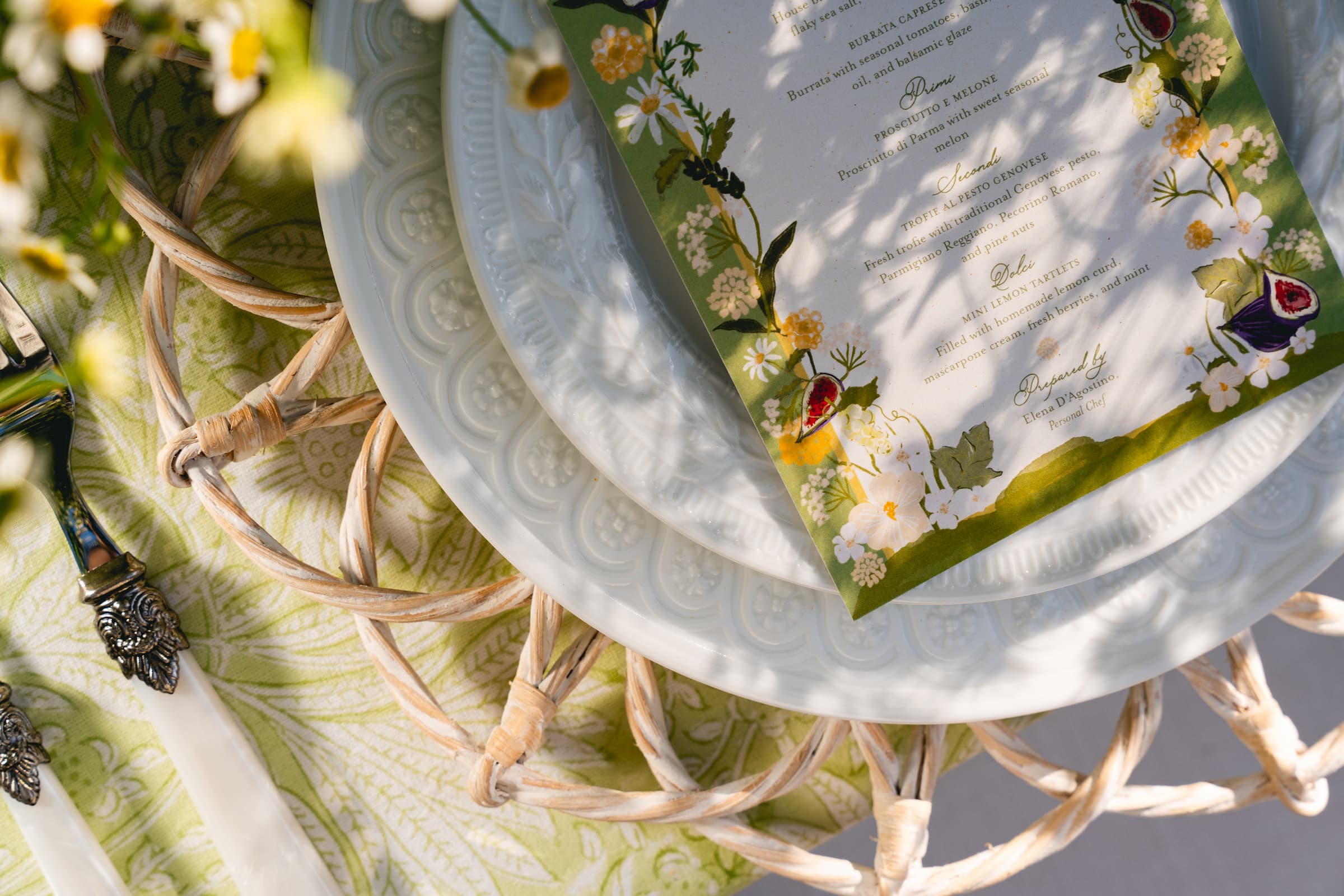 Citron block-printed cloth beneath an illustrated menu and rattan charger
