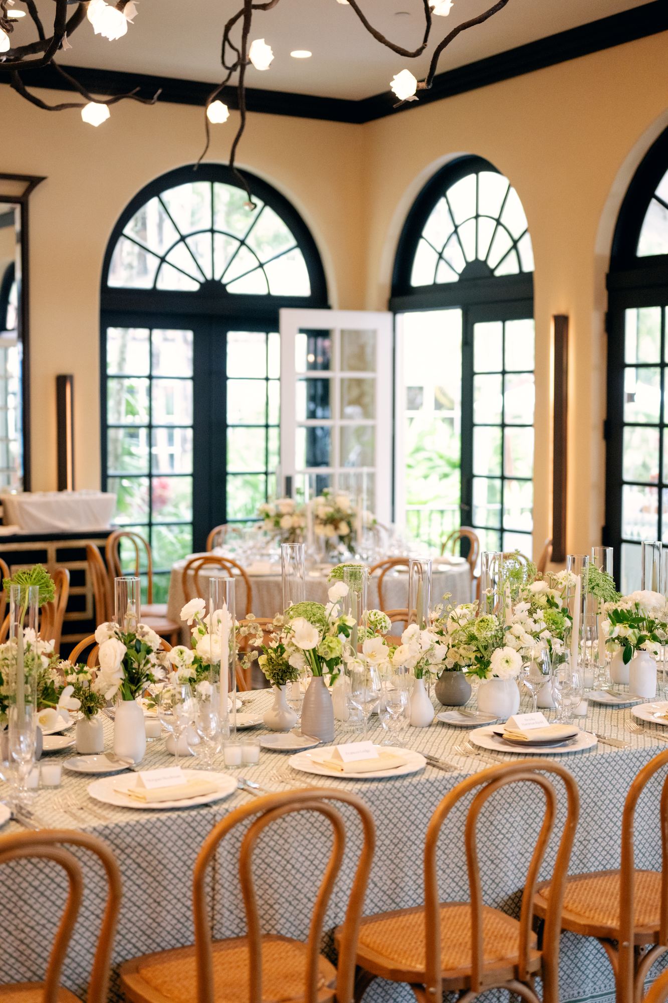 Reception room with arched windows, branch chandelier and printed tablecloths