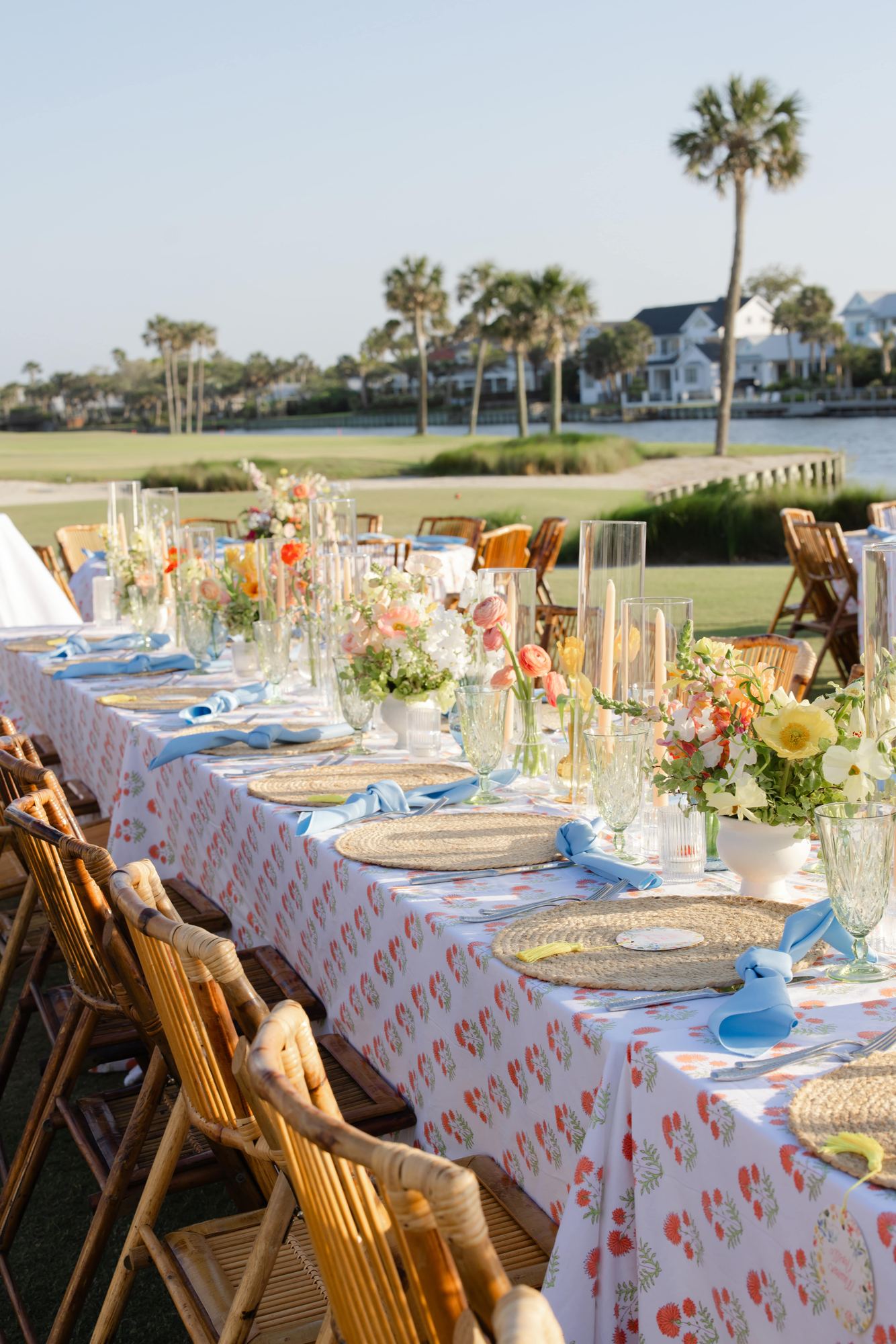 Place settings with woven chargers and blue knotted napkins on coral block print