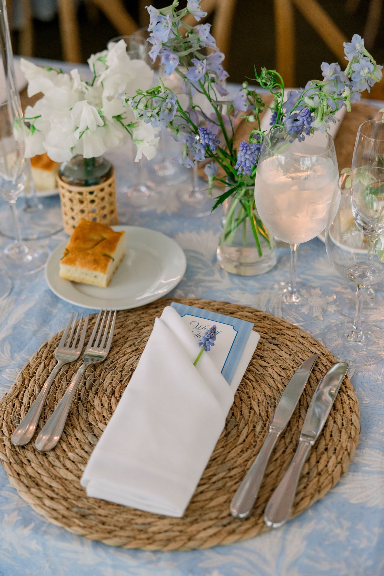 Place setting on a pale blue block-printed cloth with a woven charger and blue menu