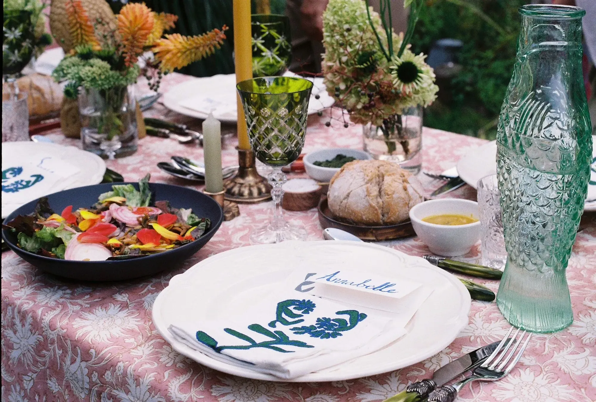 Garden dinner table under a pink block-printed cloth with embroidered napkins